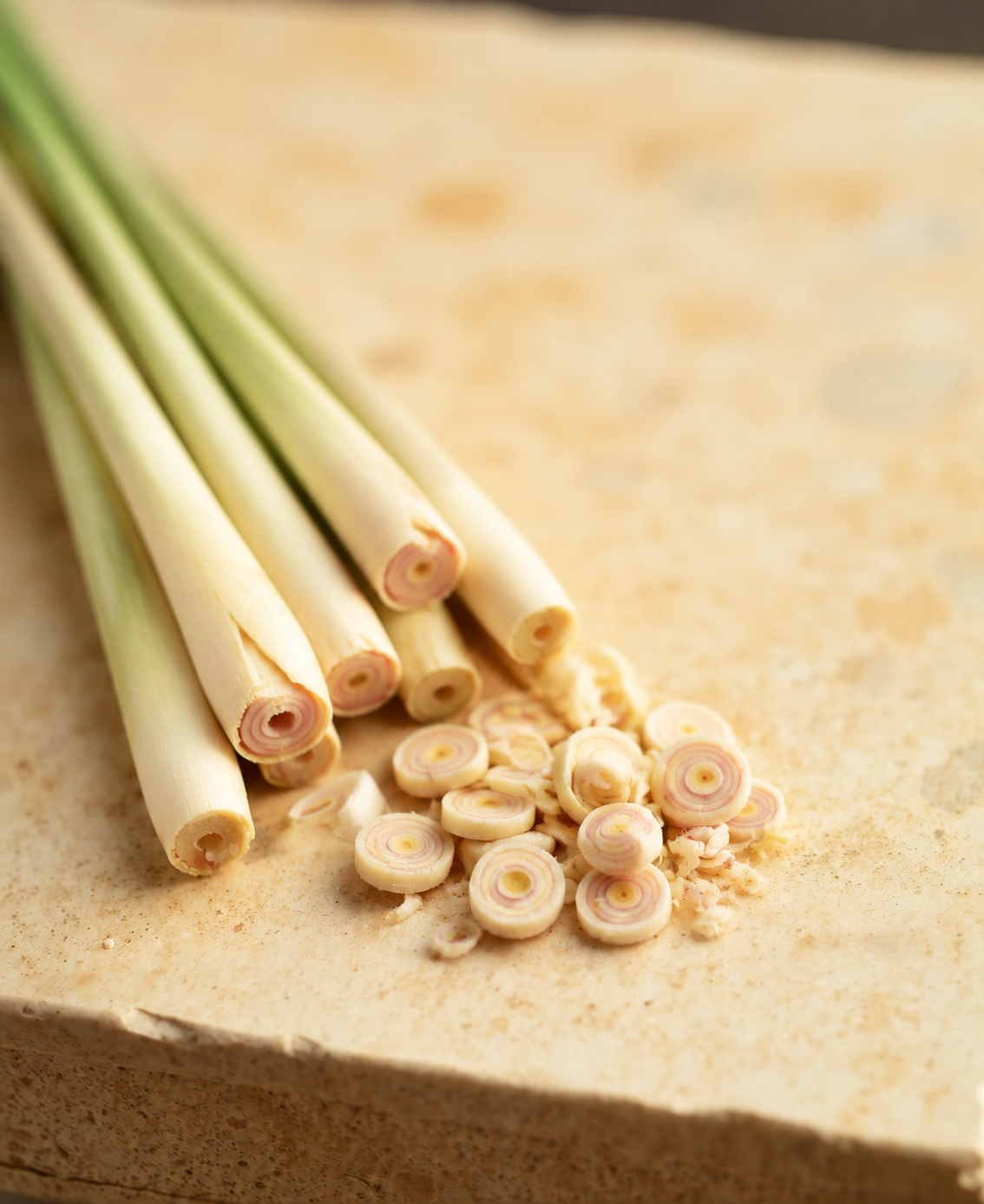 Fresh lemongrass stalks on a warm cream stone surface