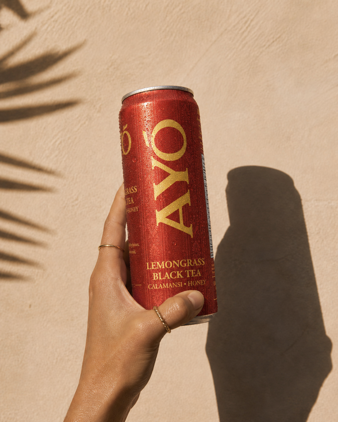 Hand holding a chilled AYÓ can covered in condensation in bright sunlight