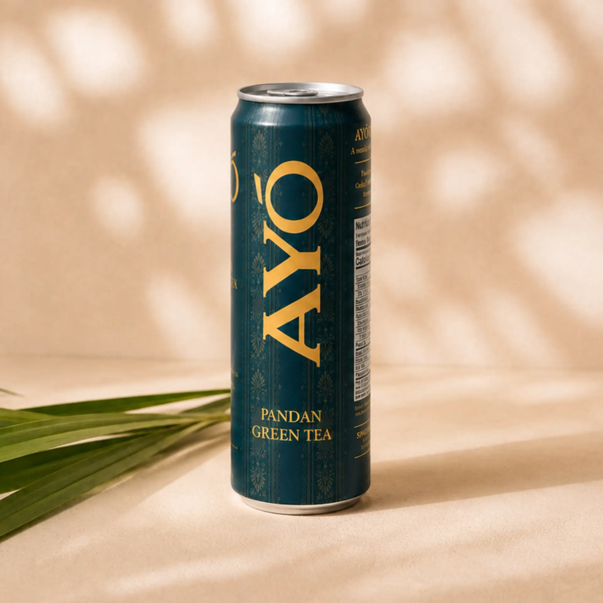 AYÓ Pandan Green Tea can beside fresh pandan leaves on a cream surface